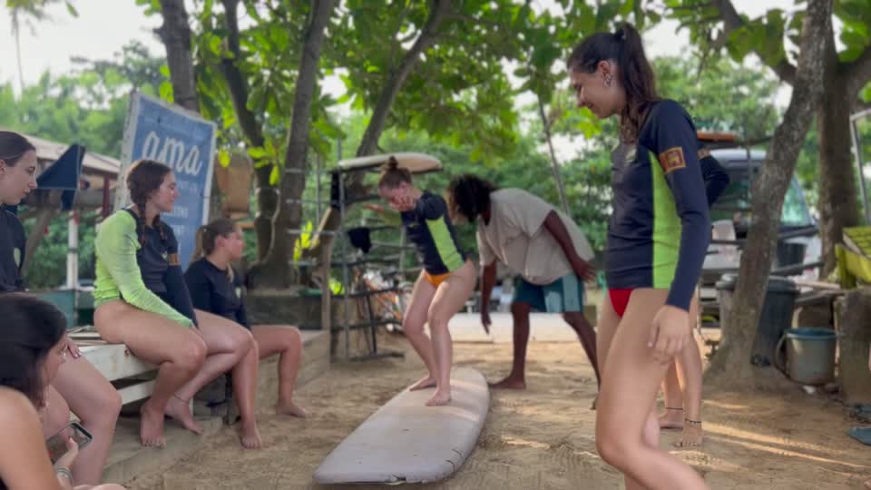 Lahiru guiding a student through pop-up practice on the sand in Weligama